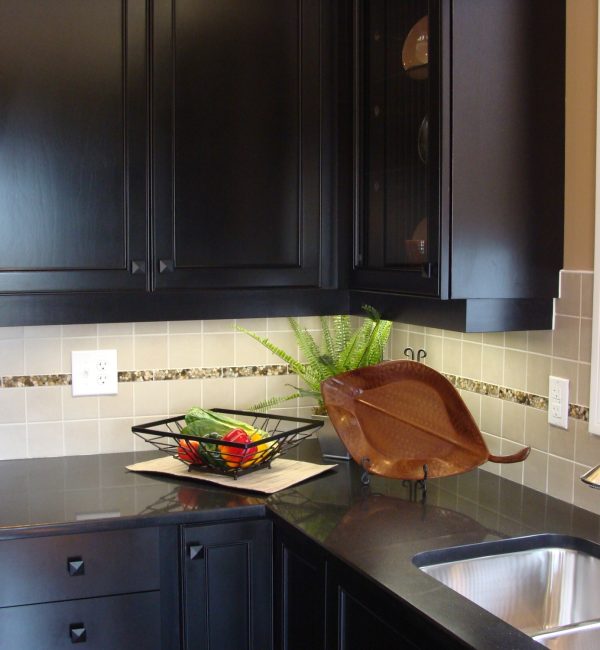 Modern kitchen design in dark color for visual impact, black granite countertops, undermount sink